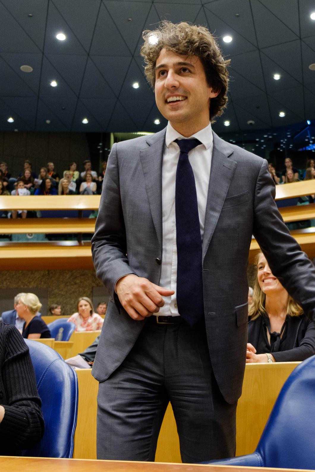Jesse Klaver staat met een glimlach bij zijn stoel in de Tweede Kamer